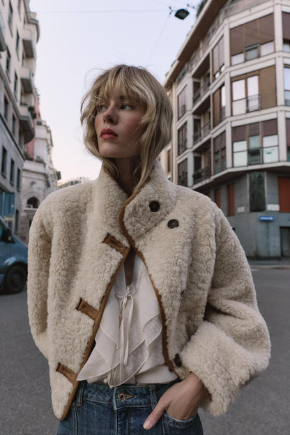 frau trägt beige teddyjacke mit knöpfen auf der straße