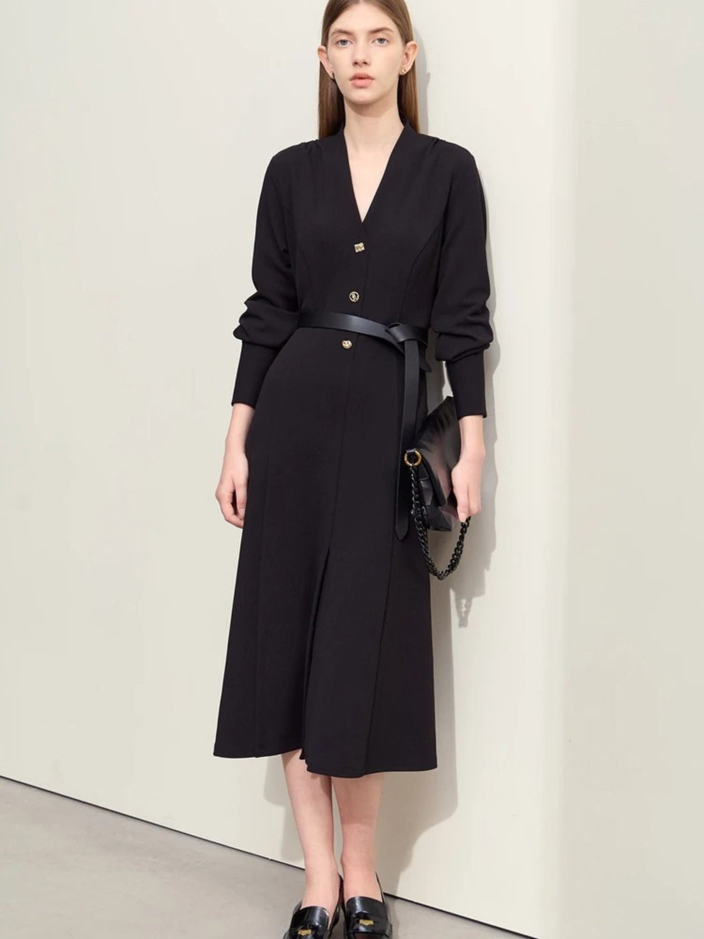 Schwarzes Midikleid mit V-Ausschnitt, Modell frontal mit Tasche.