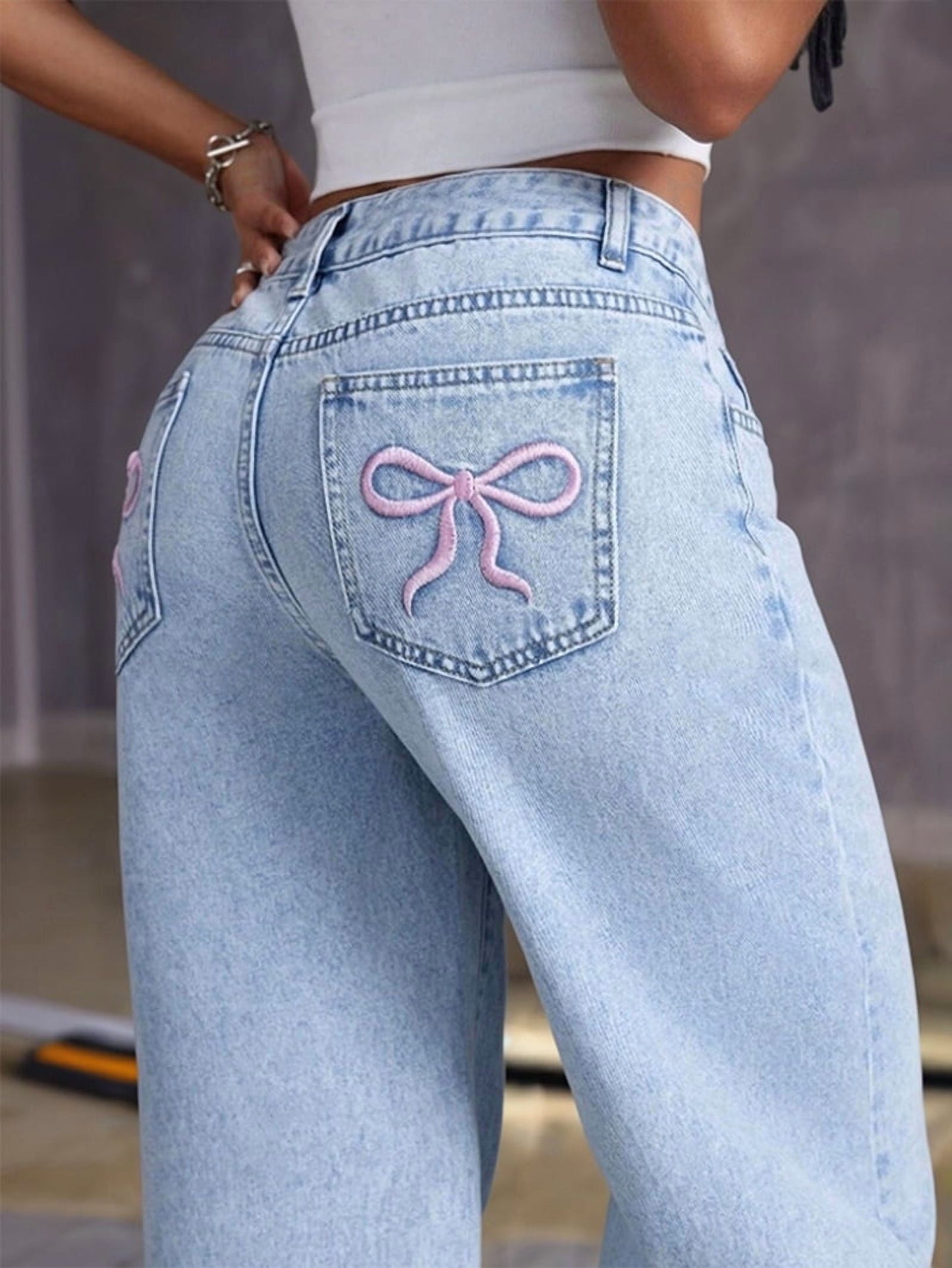 Detailaufnahme der Gesäßtasche mit gestickter Schleife auf Jeans
