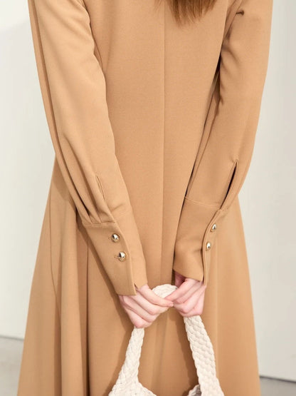 Detailaufnahme: Ärmeldetail mit Goldknöpfen am beigefarbenen Kleid.