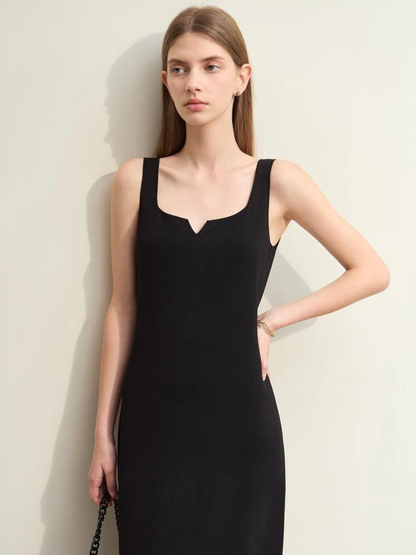 A woman wearing a simple, minimalist, sleeveless midi dresses with a v-cut out in the neckline in black. 