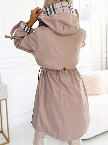 Khaki Trenchcoat mit Kapuze und Karodetail, offen getragen.