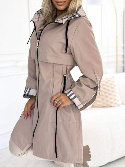 Khaki Trenchcoat mit Kapuze und Karodetail, offen getragen.